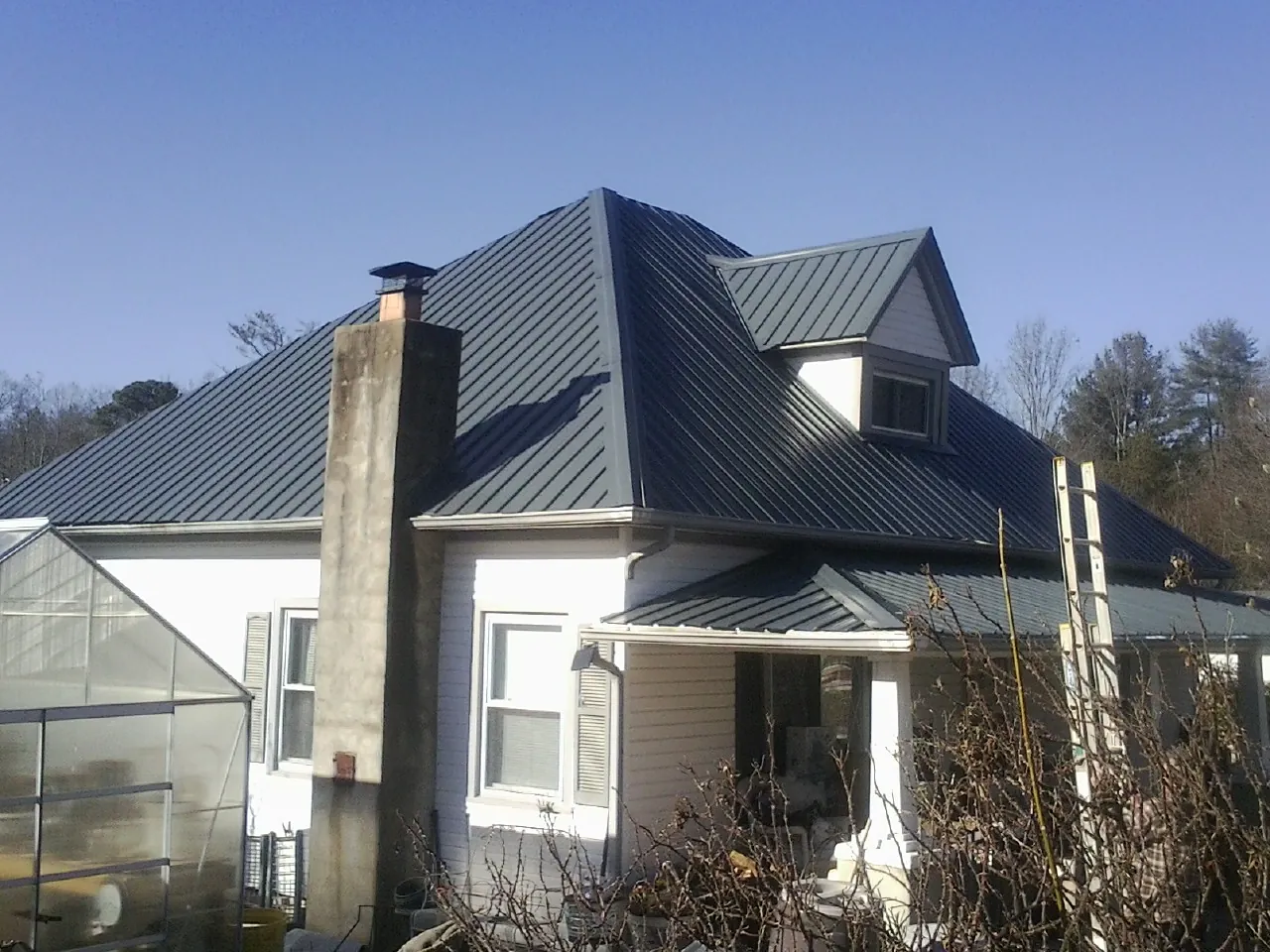 Dark blue standing seam metal roof on a white farmhouse with dormer — Slate & Tile Roof Repair by Roofing Brothers in South Cle Elum