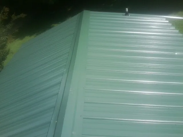 New green metal panels meeting at the ridge of a roof — Flat Roof Repair work by our crew in South Cle Elum