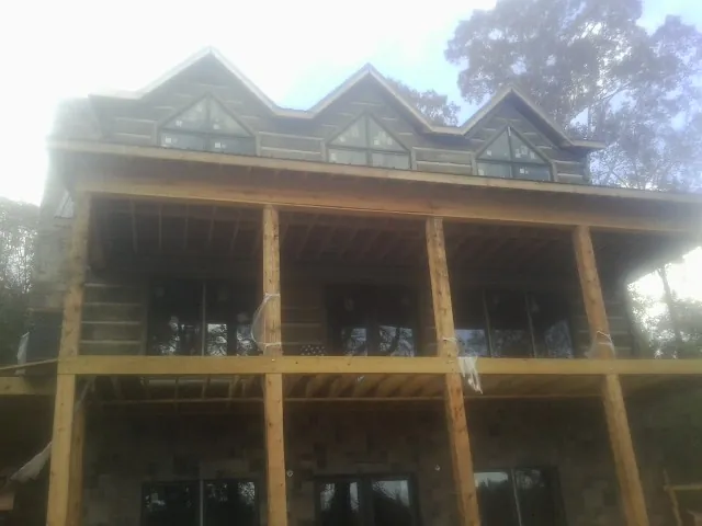 Dormers and porch framing on a large log home under construction — Roof Coating work by our crew in South Cle Elum