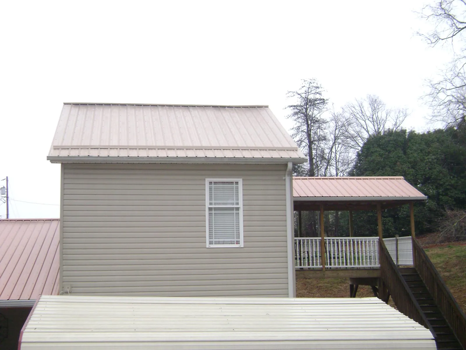 Tan metal roofs on a two story addition and attached porch, from a Roof Replacement job in South Cle Elum